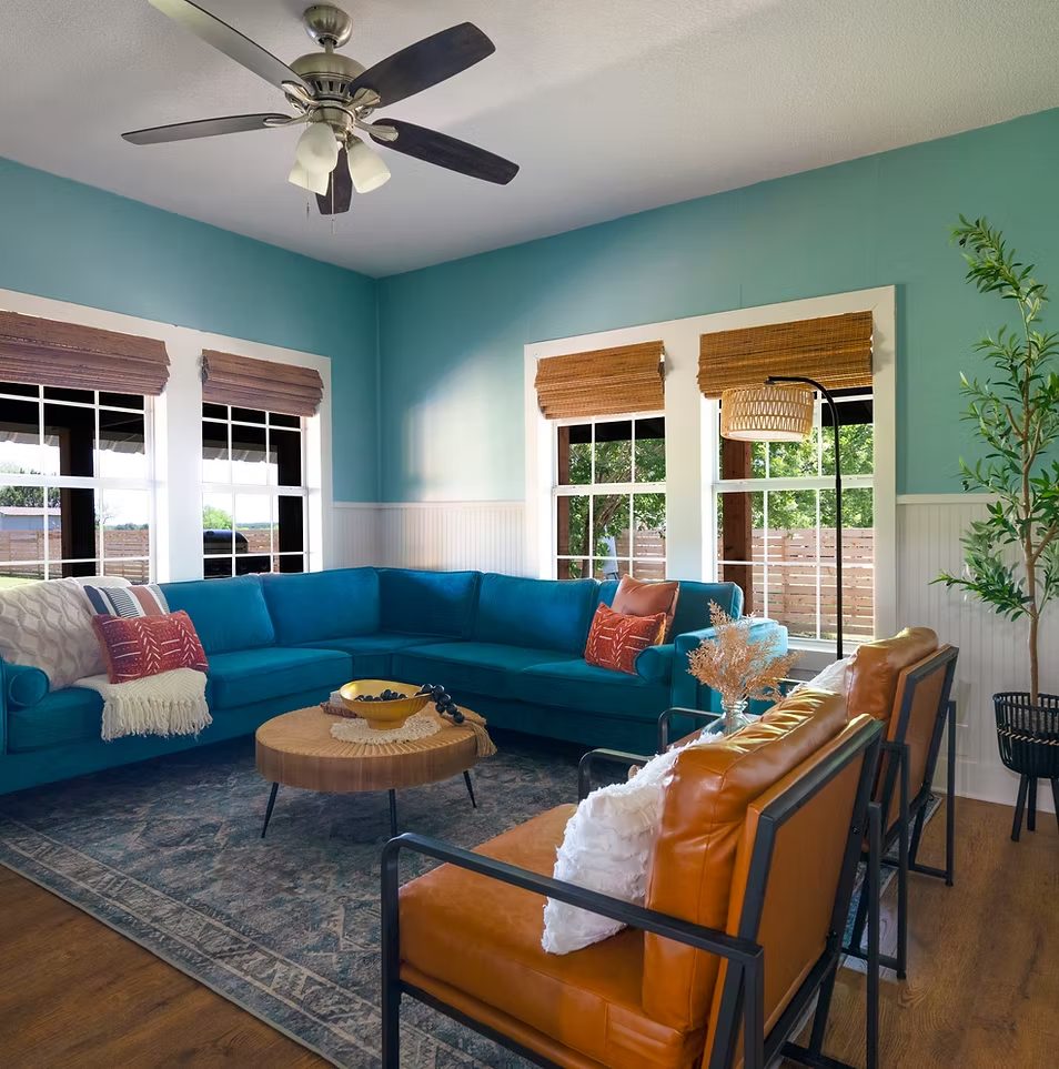 Elevated short-term rental living room with teal accent wall and tan leather chair — interior design by Cynthia Stays Curated
