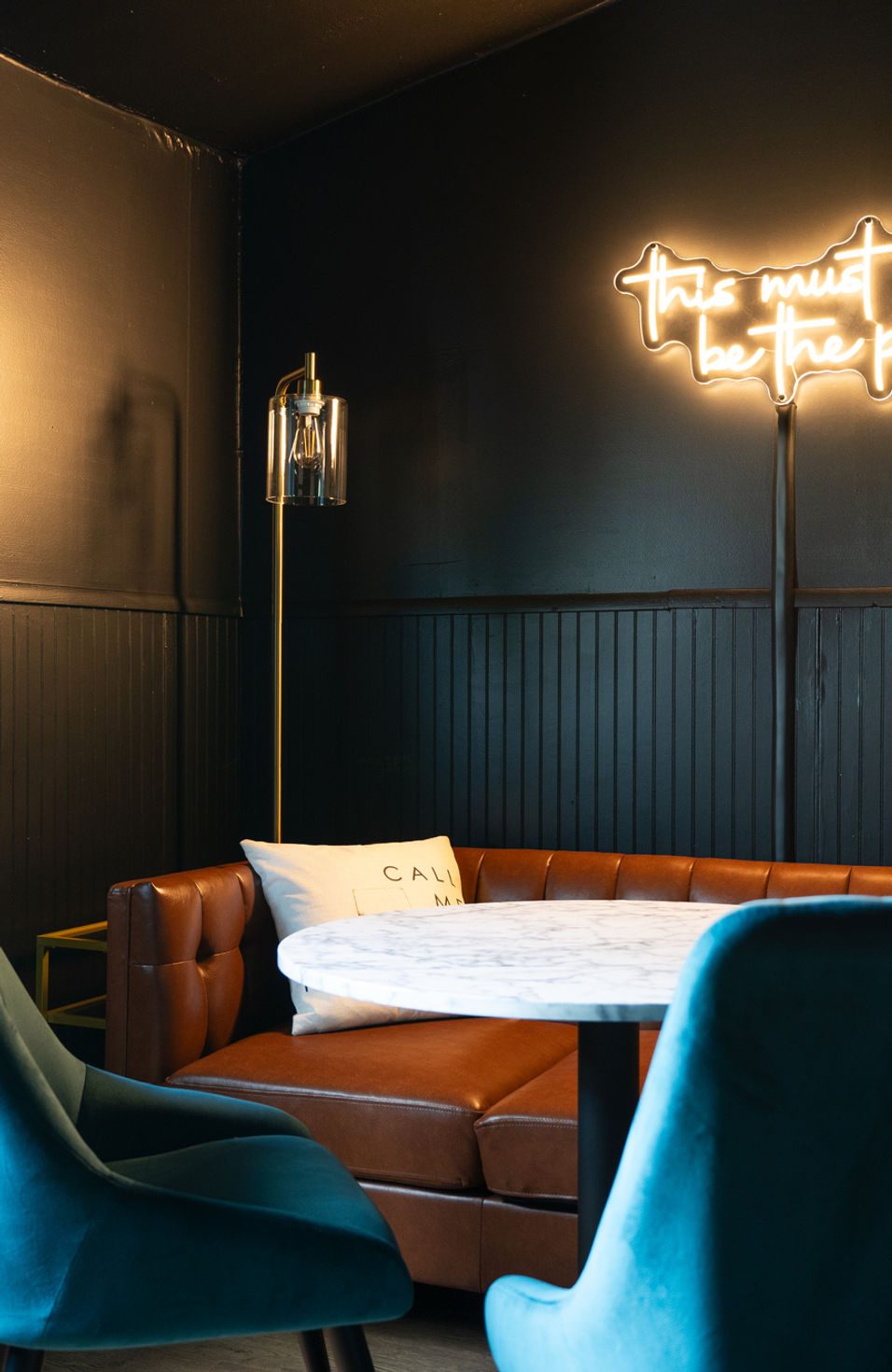 Short-term rental dining area with velvet chairs and neon sign — Execute design package
